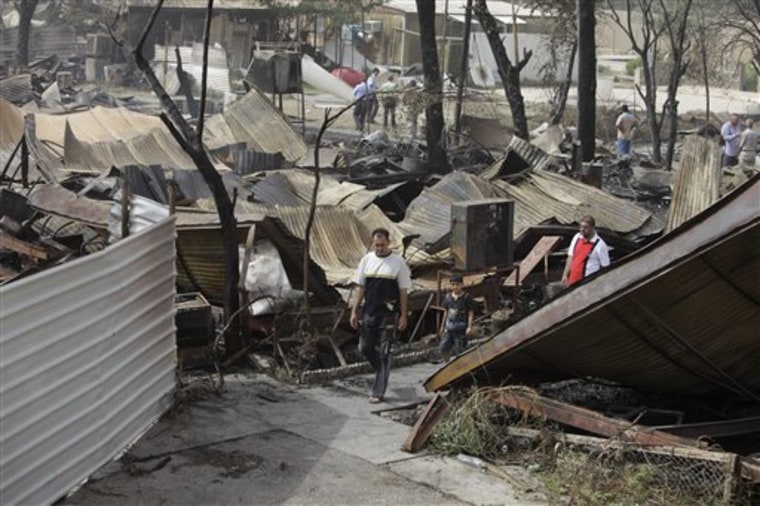 People inspect the scene of rocket attack at a residential complex in Baghdad, Iraq, Tuesday, July 5, 2011. Several Iraqis have been killed and wounded in a late night rocket attack on Baghdad's heavily fortified Green Zone, officials said.  (AP Photo/ Karim Kadim)